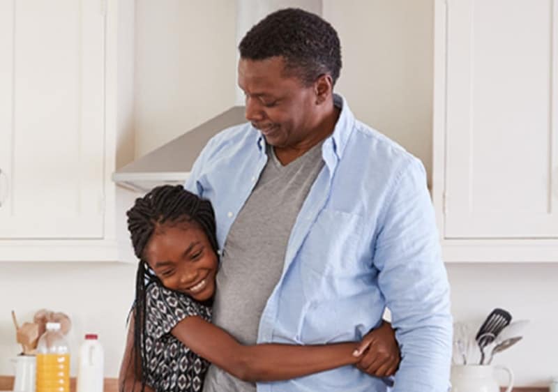 A man with diabetes who is at risk of chronic kidney disease hugging his daughter. 