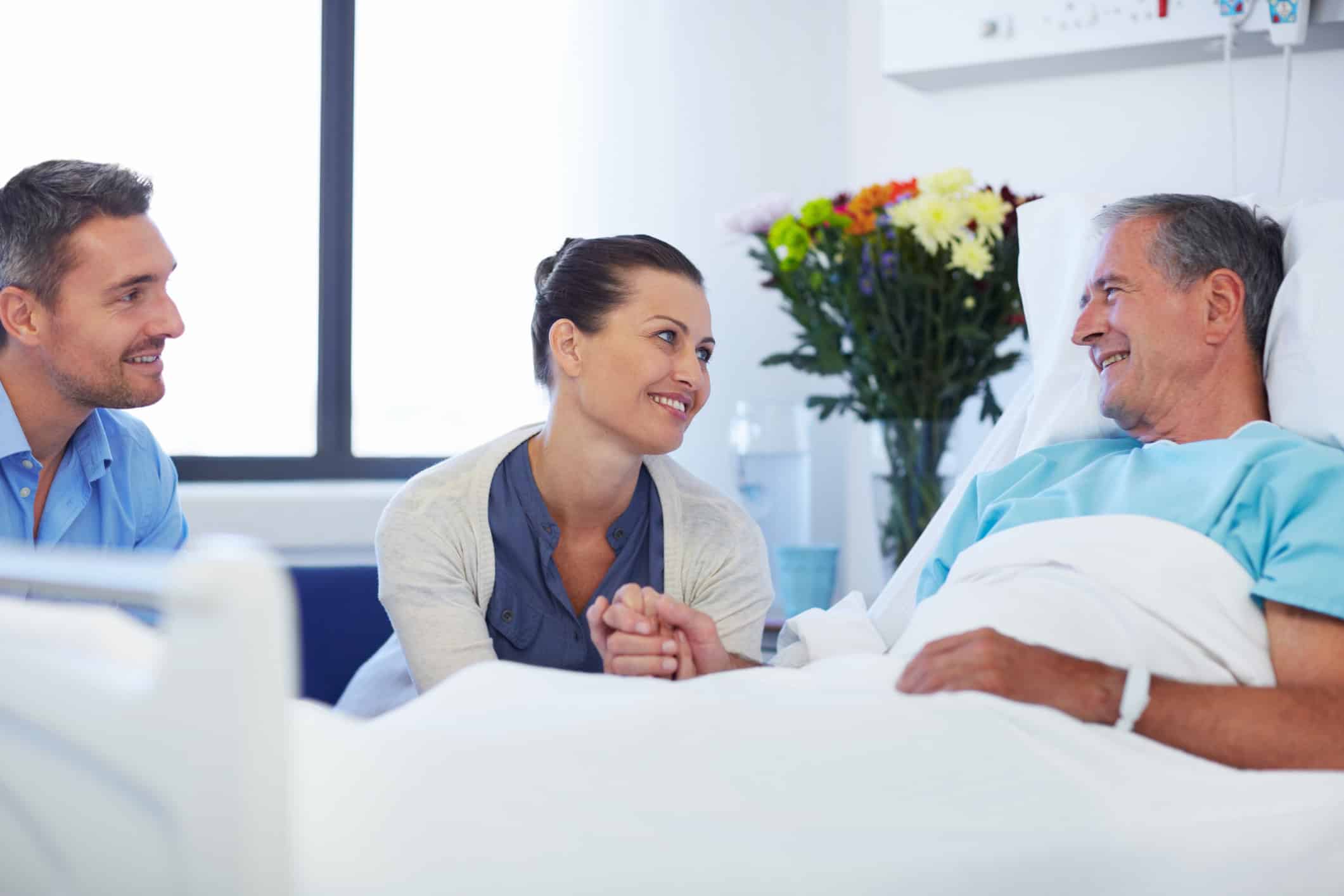 Senior patient receiving a visit from his adult children while in hospital
